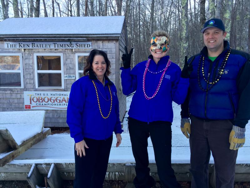 Getting into the Mardi Gras spirit and checking the chute in preparation for the 2016 U.S. National Toboggan Championships are, from left, June Parent, executive vice president and senior retail banking officer for Camden National Bank; Jody Landrith, Camden Main Office branch manager; and Andrew Dailey, Toboggan Committee member.