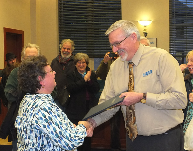 Camden Postmaster Stephan P. Dalessandro presents Perry with a certificate from District Manager John Galusky, thanking her for her years of service.