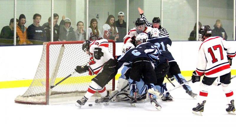 A player (#5) and Chase Matteo (#4) battle for a loose puck among a host of Old Town/Orono defenders as line mate Kieran Lydon (#17) holds the top of the low slot. The puck did go into the net shortly afterwards, but the goal was disallowed because the referee lost sight of the puck. (Photo Courtesy of Molly Cole)