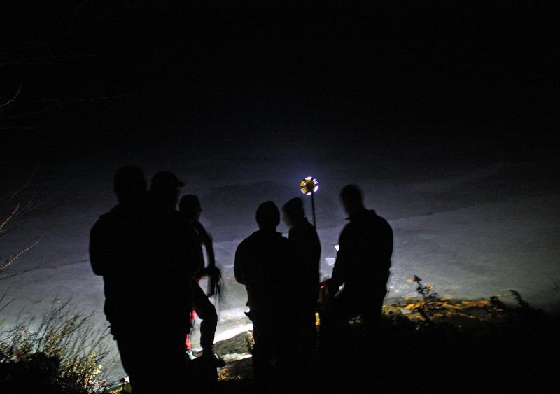 Lit by a strobe and flashlights, it was nearly impossible to pinpoint where Trueman Moore went through the ice on Megunticook Lake Tuesday night before he slipped underwater. (Photo by Holly S. Edwards)