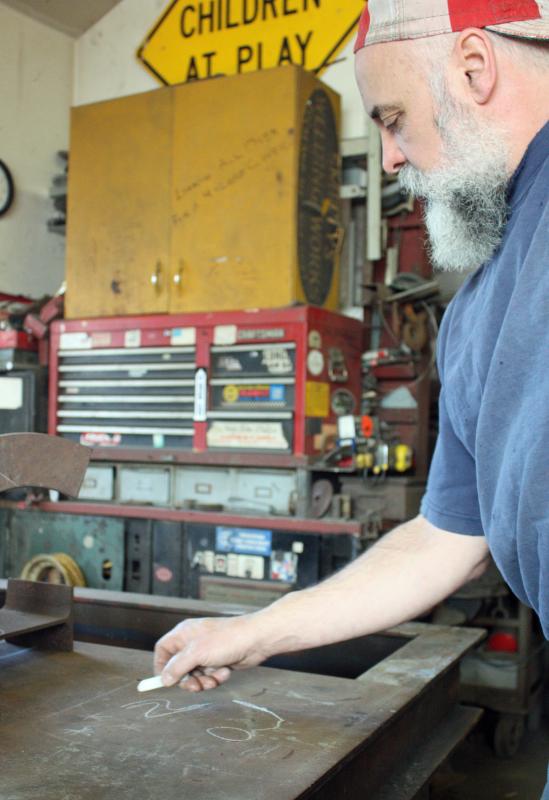Jay Sawyer sketches out an idea on a steel table in his studio in Warren. (Photo by Holly S. Edwards)