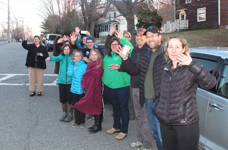 Parents wave goodbye as the students pull away from the school.