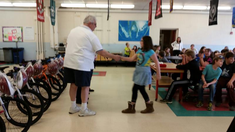 Jeff Sukeforth shares a handshake with a fifth-grade student receiving her certificate of achievement.