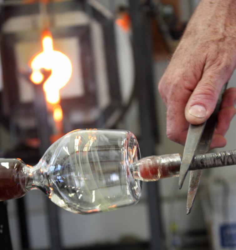 A punty is temporarily attached to the bottom of the glass, to work can begin opening the top and applying the lip wrap around the drinking edge. (Photo by Holly S. Edwards)