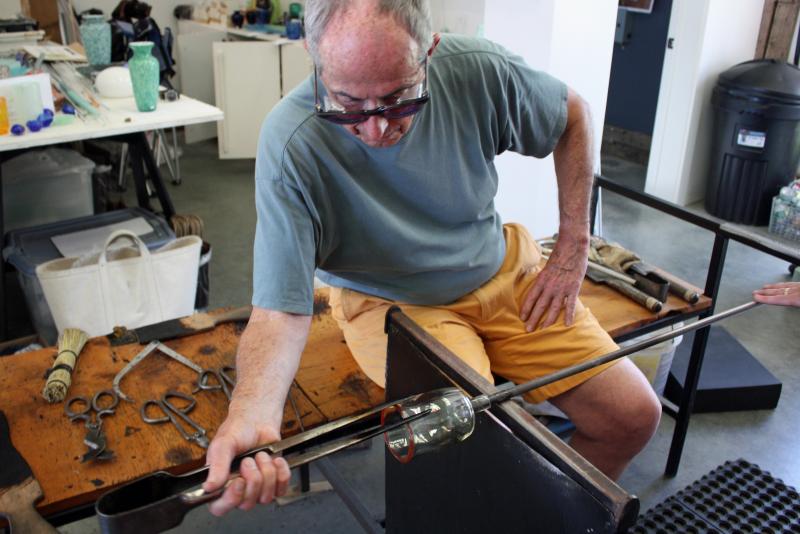 Richard Anderson uses a jack, or large tweezer, to shape the side of the glass while David Jacobson keeps the glass spinning. (Photo by Holly S. Edwards)