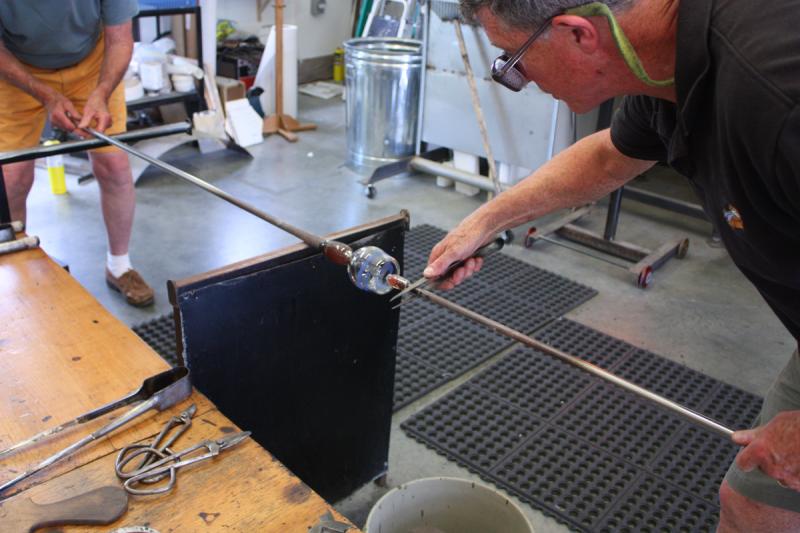 Applying a punty to what will be the bottom of the drinking glass, so the top can be opened and the glass further worked and shaped. (Photo by Holly S. Edwards)