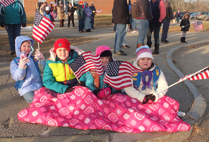 Daisy Swindler, Logan Bailey, Lilly Simmons and Avery Bailey brave the cold to wave a flag.