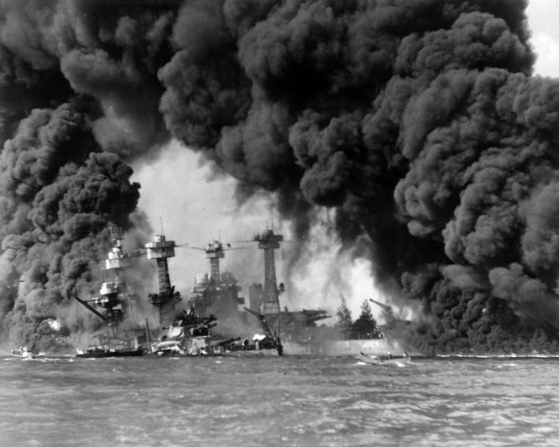 The U.S. Navy battleships USS West Virginia (BB-48) (sunken at left) and USS Tennessee (BB-43) shrouded in smoke following the Japanese air raid on Pearl Harbor.