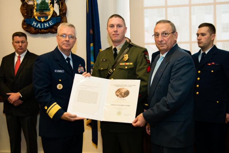 Gov. Paul R. LePage and Rear Adm. Steve Poulin awards Sgt. Matt Talbot the Certificate of Valor in the Maine State House on Tuesday, March 28, 2017. Talbot received the award for actions he took when a 40-foot lobster boat began operating in an uncontrolled manner dangerously close to the rocky shore and local maritime traffic. (U.S. Coast Guard photo by Petty Officer 3rd Class Andrew Barresi)