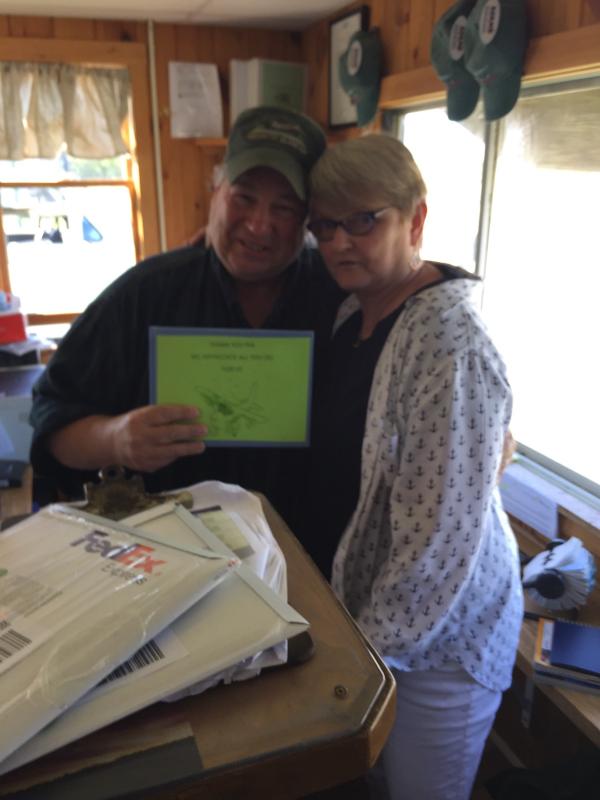 Jeannie Conway, of Vinalhaven (right) makes a surprise visit the Kevin Waters, owner of Penobscot Island Air, at the Knox County Regional Airport at Owls Head. She hands him a guest book filled with messages for Waters and the PIA crew, and some cash stuffed in the back. (Photo courtesy Jeannie Conway)
