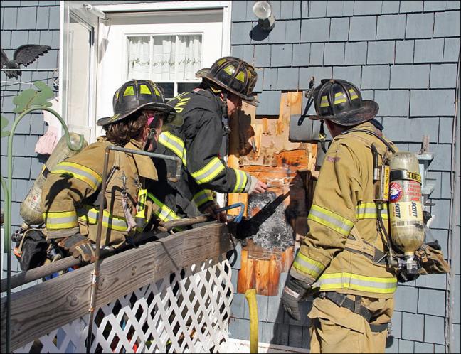 From left, Rockland firefighters Katy Vanorse and Mike Cole and Lt. Jamie Leo work to put out a fire burning outside 10 Frederick St. early Monday afternoon. (Courtesy Rockland Fire Dept./by Alan Athearn)