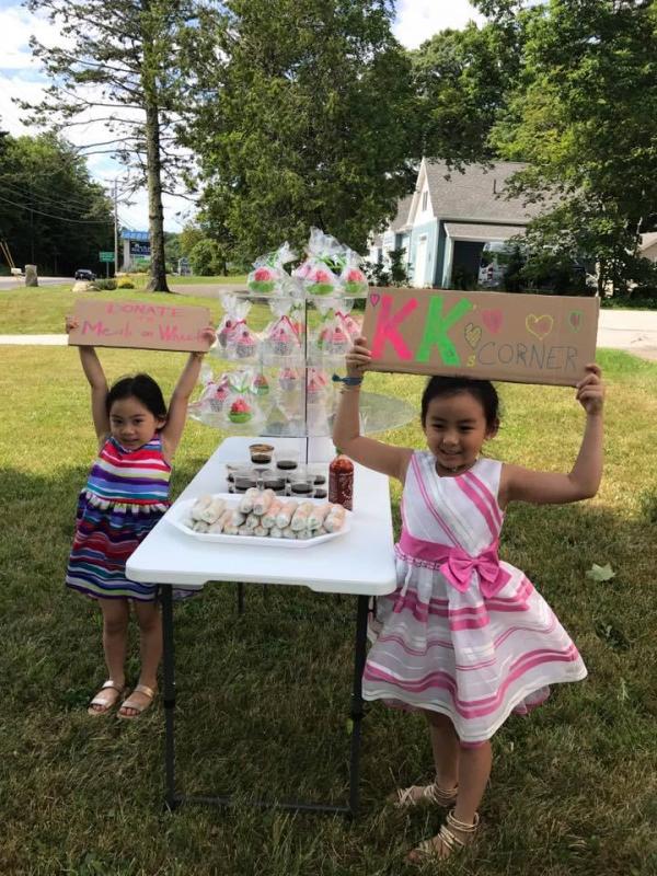 Kaidi (left) and Kaida Nguyen hold signs to promote their fundraiser for MCH Meals on Wheels, at KK’s Corner, the name of their fundraising spot at Tropical Nails in Rockport. (Photo courtesy of Tracie Nguyen)