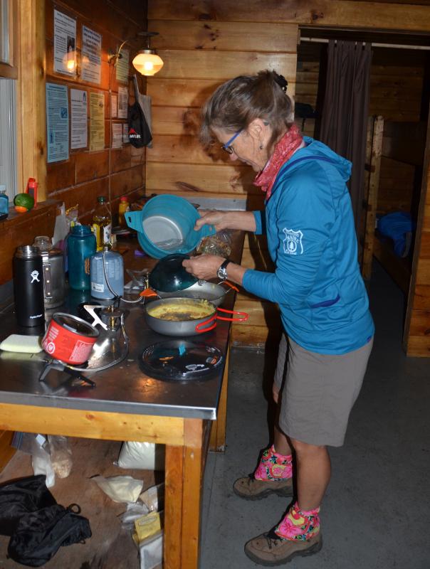 Emily Davis, MaineSport guide, makes dinner in the bunkhouse at Chimney Pond. (Photo by Lynda Clancy)