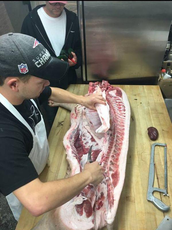 Mallett (upper left) teaching an employee how to break down a pig. (photo courtesy of Elliot Weiner)