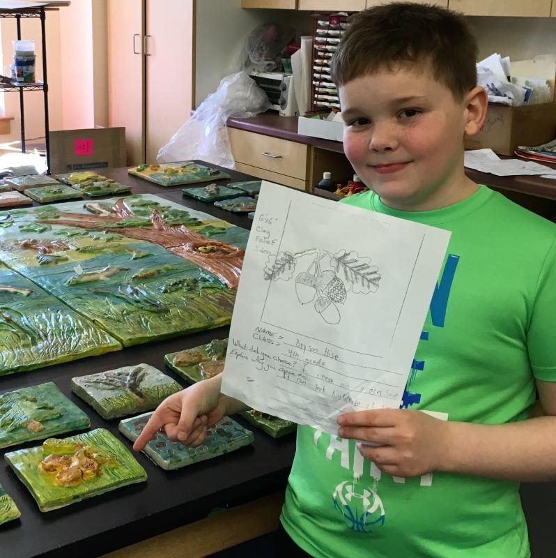 Fourth grade student Bryson Hise holds the drawing that inspired his clay relief. (Photo courtesy Randy Fein)
