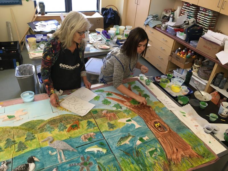 Randy Fein helps a Lincolnville student Marlie Berard wit painting her relief owl. (Photo courtesy Randy Fein)