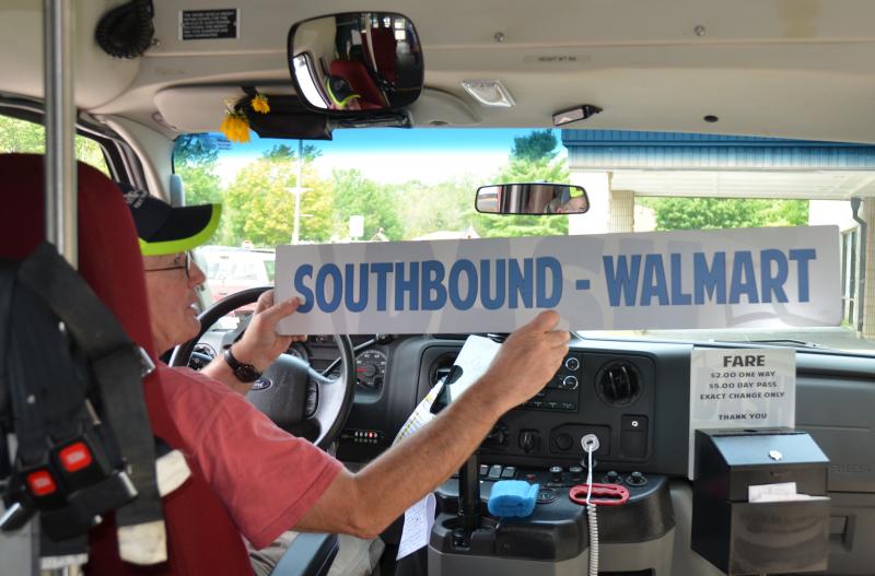 Mike Ray flips the sign that rides in the DASH bus window, letting passengers know that he is heading to Walmart in Thomaston, or back to Pen Bay Medical Center in Rockport. (Photo by Lynda Clancy)