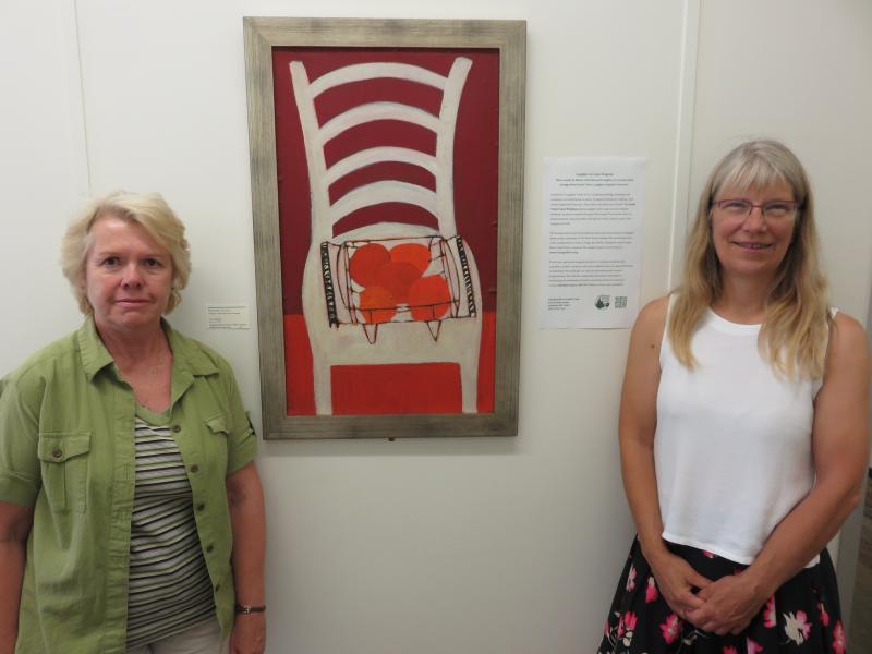 Sherry Reimer, Housing Coordinator , MCH, Inc. and Annette Naegel, Director of Conservation, Georges River Land Trust with oil painting by Bernard Langlais. (Photo courtesy of GRLT)