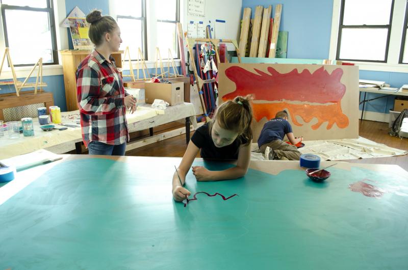 Youth mural artists Kayla Betts (left), Eliza Fournier (center) and Liam Burlingham practice design and technique on a large abstract painting at partnering site, Flanagan Community Building, in downtown Rockland. Oceanside Middle schoolers in Arts with Heart will be creating murals for several sites across the community including the Rockland Transfer Station and The Landing Place. (Photos courtesy of Arts in Action)