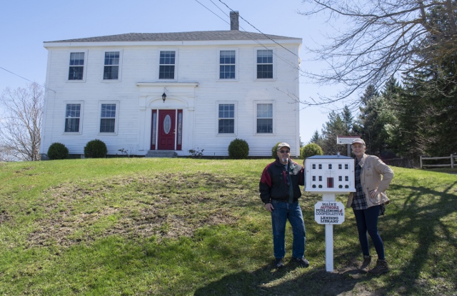 Jane Karker, president of Maine Authors Publishing, and Joseph Cueto stand with the lending library after it was installed by Claybrook Landscaping Inc. (Photo courtesy Maine Authors Publishing)