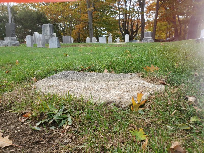 Walter Guptill pondered over this old concrete foundation for the Bennett stone that remains on the Bennett family lot. According to records, the gravestone read: “E. Bennett and Family.” There was no other information on the stone. (Photo by Walter Guptill)