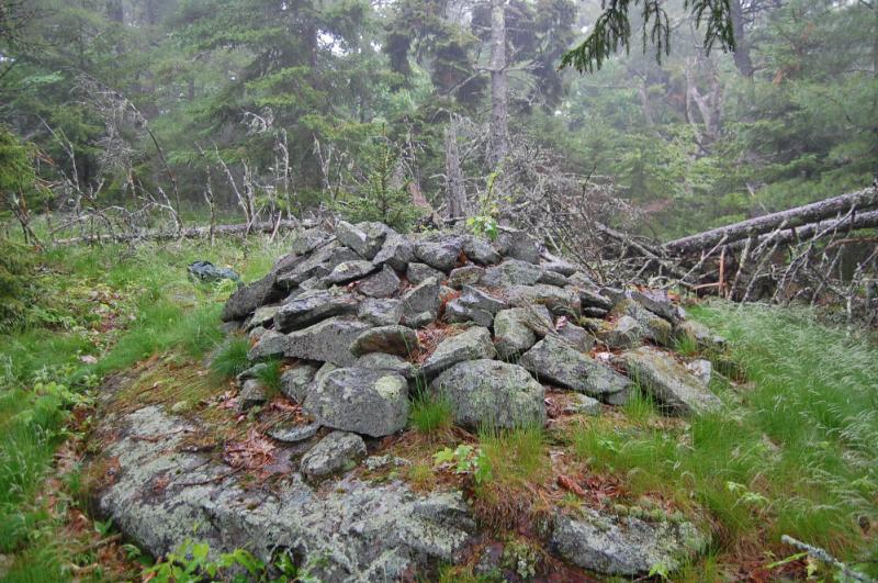 This large cairn occupies a flat area at the top of Ducktrap Mountain. It appears to be part of a grouping of stone structures aligned in a linear arrangement, including two large stacked stone structures, as well as a natural formation which has been used as a fire pit or altar in the past.
(Photo courtesy Dennis Cerrotti)