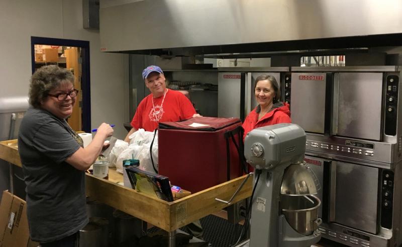 Nutrition director, Susan Dodge (in the black T-shirt) and two school nutrition workers, Bonnie Box and Allan Brown prepare meals for delivery. (Photo by Deb McIntyre)