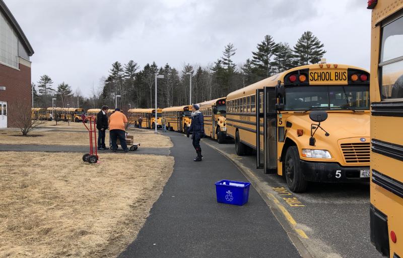 Bus drivers line up to receive the meals, which they will distribute to students along their regular bus routes. Transportation Director Julie Waters oversees the logistics. (Photo by Lynda Clancy)