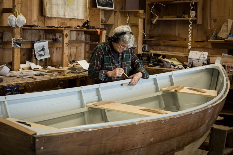 Susan St. John works on scribing the curve of her boat onto small spacer blocks that will provide extra support for her oarlocks. St. John finished and launched her skiff, Tenacity, in December of 2019. Now, she is back at the Apprenticeshop building a sailing rig for it. (Photo by Erin Tokarz)