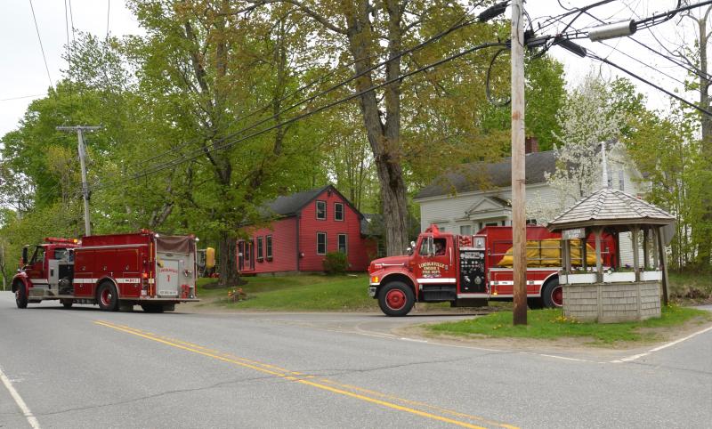 Fire trucks pass by Petunia Pump, the marking point of Lincolnville Center. (Photo by Lynda Clancy)