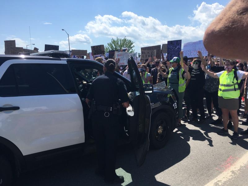 The Bangor police cruiser was met with a wall of protestors, wearing masks. The police officers were not. (Photo courtesy Molly Mulhern)