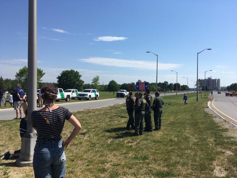 The nonmasked group of border patrol fellows who told me they were there to “keep me safe.” Their vehicles are parked on the left, with the airport fence and Air Force One in the distance beyond. (Photo courtesy Molly Mulhern)
