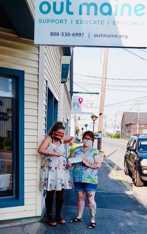 Peyton Feener (Good Tern Co-op front end manager) and Deminique Cole (Good Tern Co-op wine and beer buyer) present a check to OUT Maine. (Photo courtesy Good Tern Natural Foods)