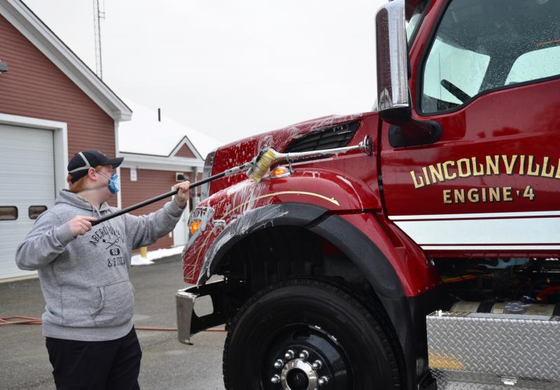 Lincolnville firefighter Cameron Freeman gets to work scrubbing down Engine 4.