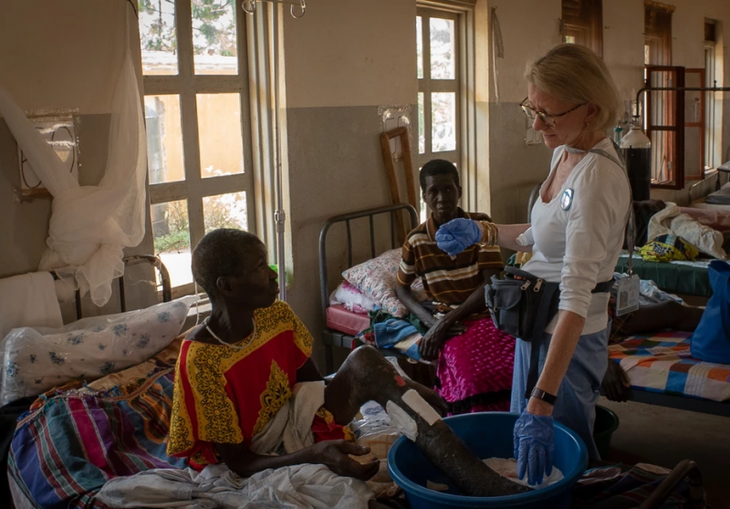Partners for World Health founder Elizabeth McLellan, standing, speaks with a patient during a medical mission to a developing nation. (Courtesy Partners for World Health)