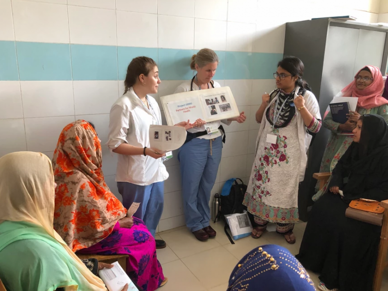 A pair of Partners for World Health volunteers, standing, educate women during a medical mission to a developing nation. (Courtesy Partners for World Health)