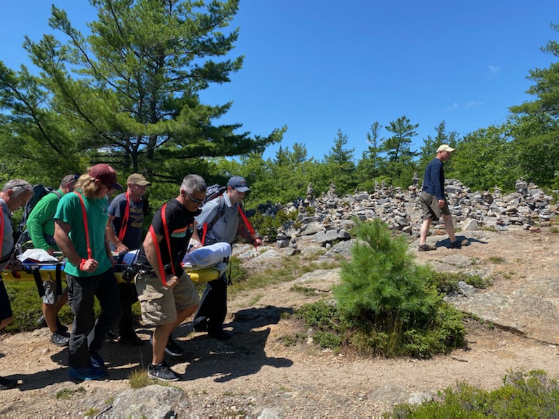 Volunteers from Camden Fire Dept., Camden Hills State Park rangers, Coastal Mountain rescue and North East Mobile Health Services help carry a man up the steep Mount Battie Trail in a Stokes basket after he suffered an ankle injury July 24, approximately half way down the face of Mount Battie. (Photo courtesy Camden Fire Dept.)