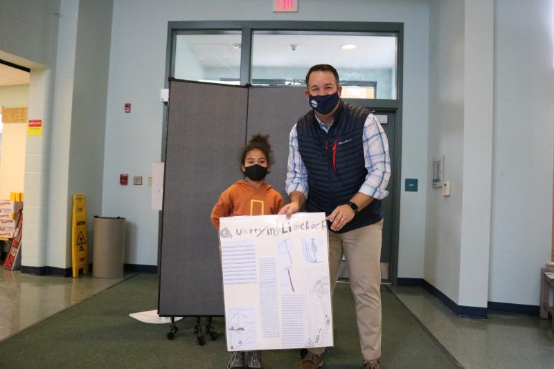 Third Grader Beatrice Mathis of Bonnie Massengale's class, presents her class poster to Rockport Town Manager Jon Duke highlighting the history of quarrying in Camden and Rockport.
