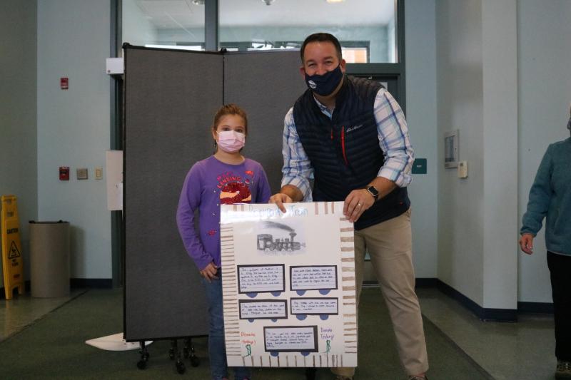 Third Grader Elizabeth Fernald, of Danielle McMenimen's class, presents her class poster to Rockport Town Manager Jon Duke highlighting the history of the trains involved in the local quarrying process.