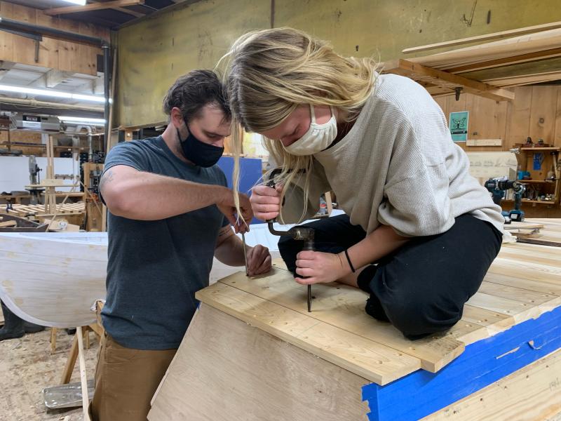 Amber and Max fasten in the last bottom plank on their Susan Skiff. (Photo courtesy The Apprenticeshop)