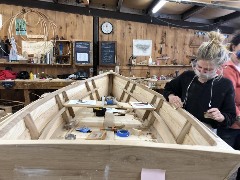 Amber does some final clean up of the interior of the skiff to prepare for oil and paint. (Photo courtesy The Apprenticeshop)