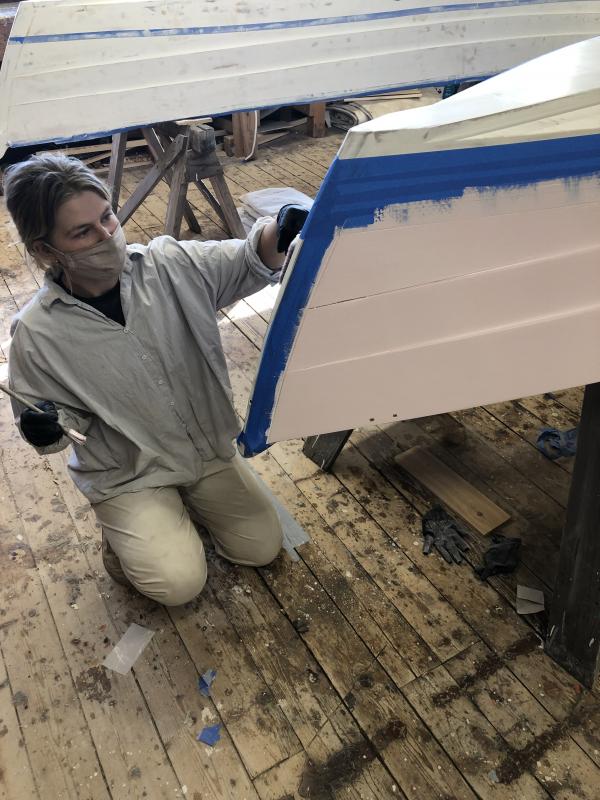 Amber applies topside paint to her skiff in the week leading up to the launch. (Photo courtesy The Apprenticeshop)