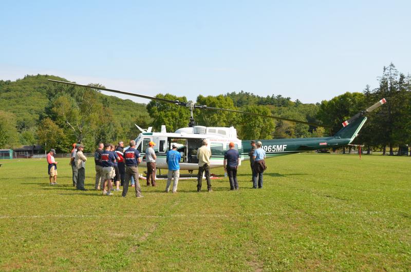 Members of the Camden Fire Dept. gather around one of the five Vietnam era UH-1H (Huey) utility helicopters owned by the Maine Forest Service and which are used for fire fighting and search and rescue. (Photo by Lynda Clancy)