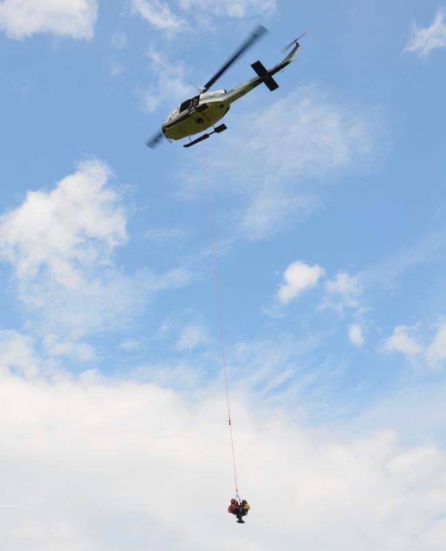 Assistant Fire Chief Andrew Lowe and District Forest Ranger Scott Maddox are exhibiting how a patient and a rescue crew lift and carry across the landscape during a short-haul rescue. (Photo by Lynda Clancy)