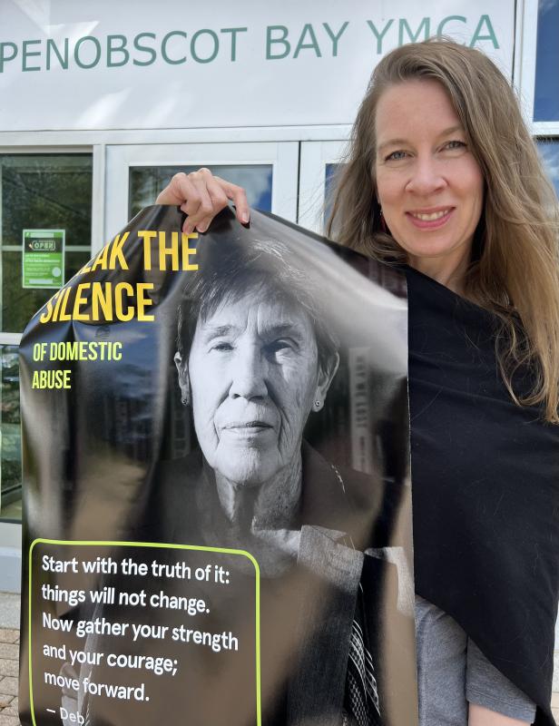 Whitney Files, CEO of the Penobscot YMCA, with the Finding Our Voices poster of author Deborah Gould, who is leading one of three Maine Humanities Council discussion groups on domestic violence, creativity and resilience. (Photo by Patrisha McLean)