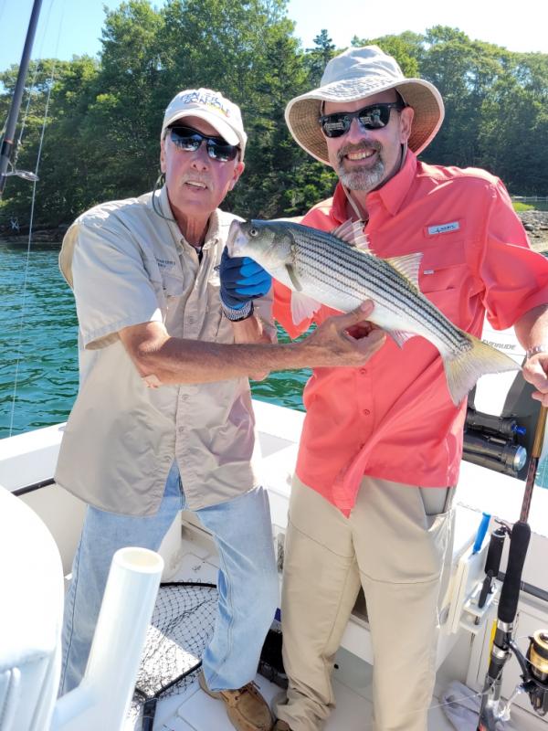 In Boothbay Harbor July 23, Barry Gibson, left, of Shark 6 Charters took Steve Jackson out fishing. Jackson, right, who is leasing the former Big Al’s Super Values in Wiscasset for his candy business, caught this striped bass. Courtesy of Steve Jackson