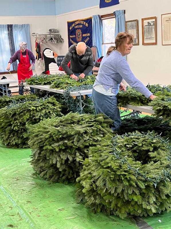 Members of Camden Garden Club painstakingly fix loops of lights to downtown lamppost wreaths. (Photo courtesy Camden Garden Club)