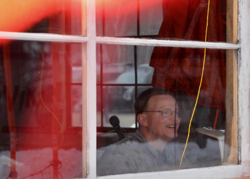 Veteran National Toboggan Championship announcer Tom Dowd at work, in the race shack at the bottom of the chute, Feb. 5, 2023. (Photo by Lynda Clancy)
