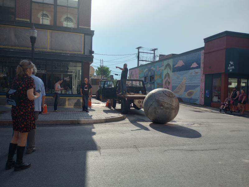 JBone rolls the ball of his Ball and Chain sculpture on to Main Street Friday evening. (Photo by Sarah Thompson)
