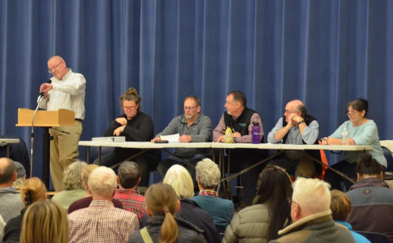 Lincolnville Town Administrator David Kinney checks his watch, noting the delayed start to the special town meeting, given how many residents showed up to vote. Beside him, Lincolnville’s Select Board: Chair Ladleah Dunn, Keryn Laite, Jr., Stephen Hand, Mike Ray and Robyn Tarantino. (Photo by Lynda Clancy)